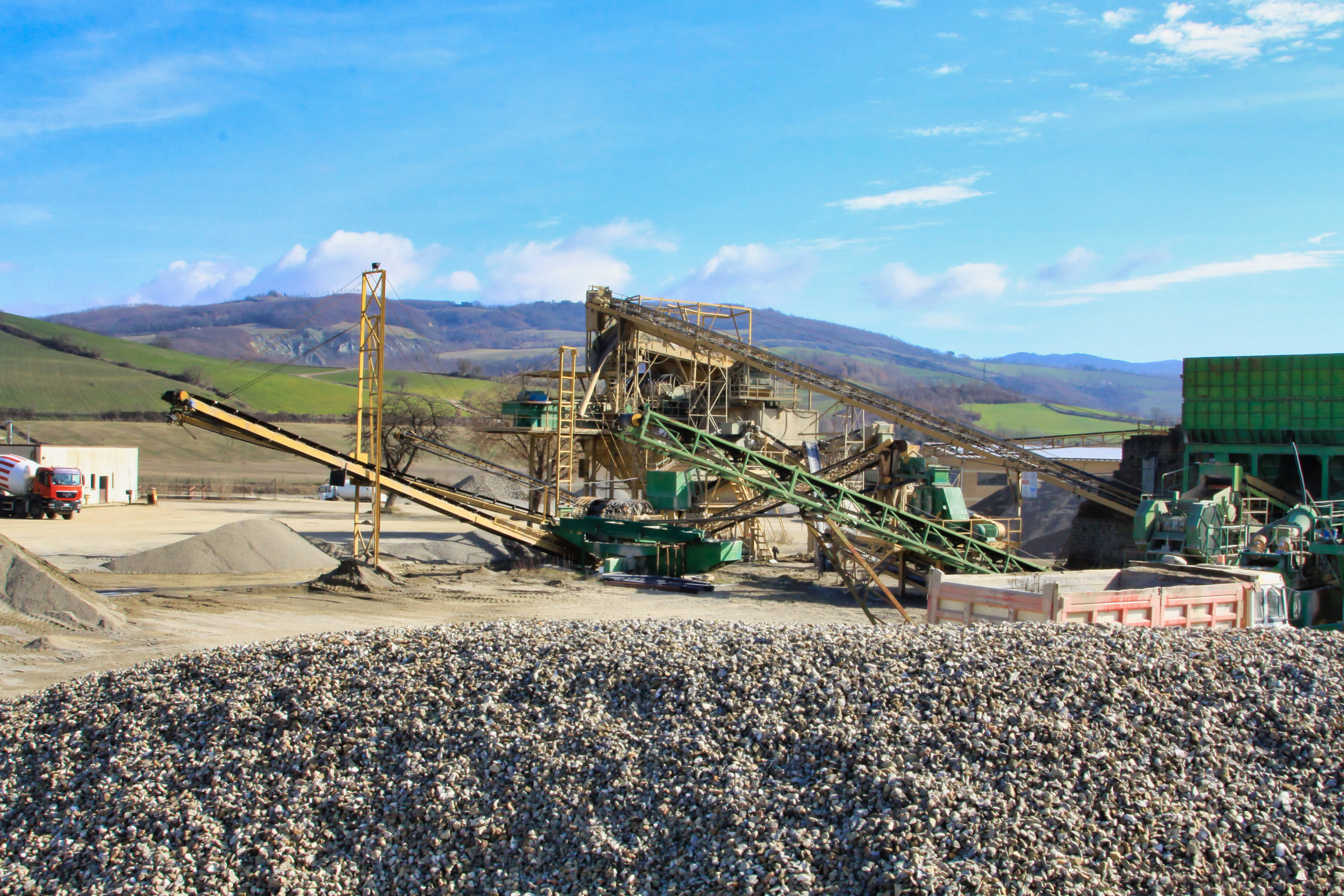 Impianto di lavorazione ghiaia in un paesaggio collinare.